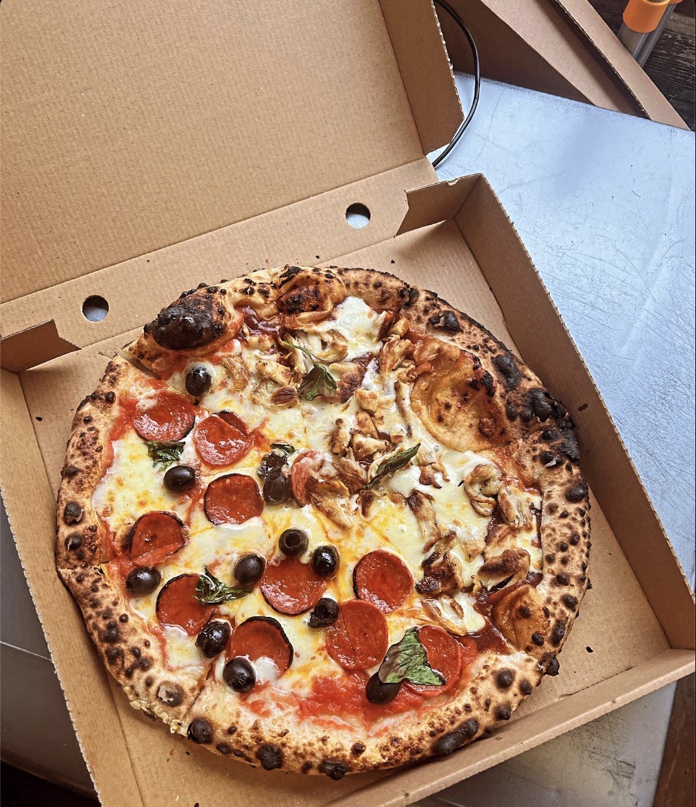 Pepperoni, chicken and olive pizza in an open box